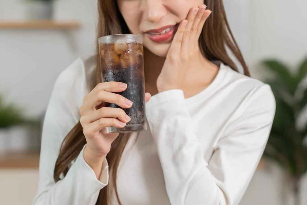 Woman Holding Cold Drink and Showing Painful Sensitivity on her Teeth | Smile Virtual