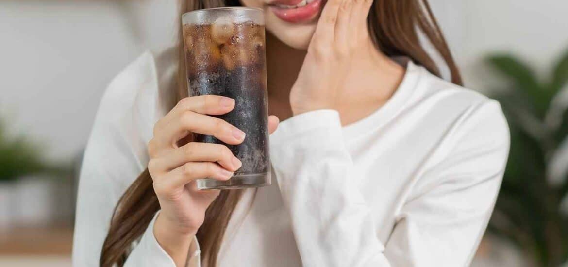 Woman Holding Cold Drink and Showing Painful Sensitivity on her Teeth | Smile Virtual