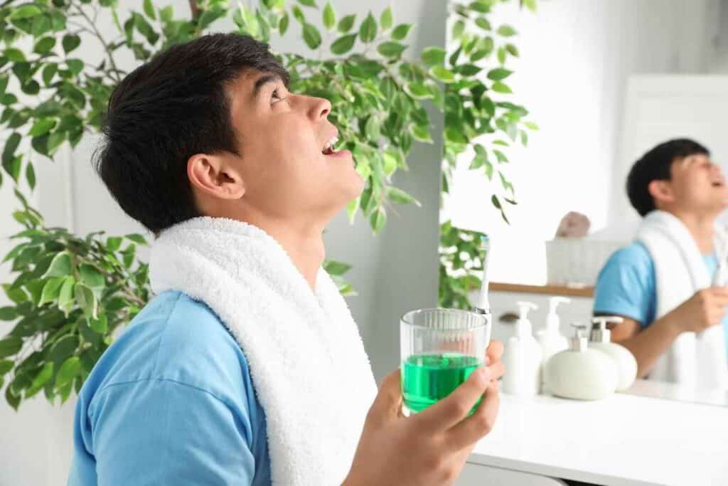 Young Man Holding Glass of Mouthwash in Bathroom | Smile Virtual
