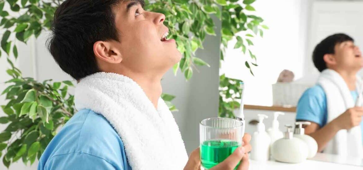 Young Man Holding Glass of Mouthwash in Bathroom | Smile Virtual
