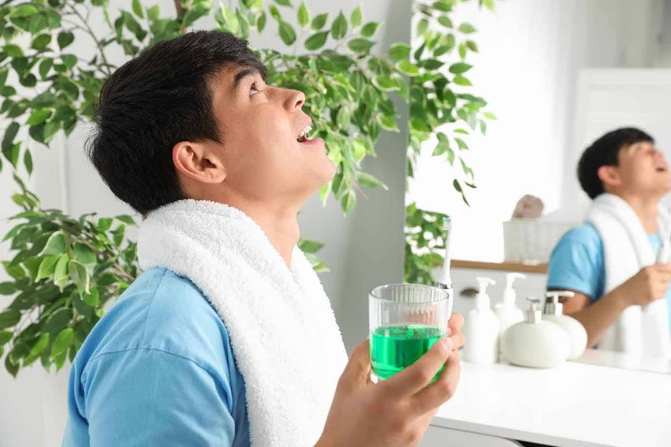 Young Man Holding Glass of Mouthwash in Bathroom | Smile Virtual